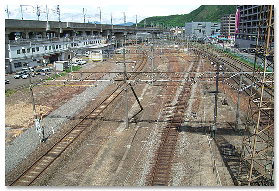 画面右から、飯坂電車×1本、JR東北本線×3本、うっすらと濃い茶色の線路跡が福島機関区への引き込み線、JR奥羽本線×1本、高架橋はJR東北新幹線　2005年11月撮影